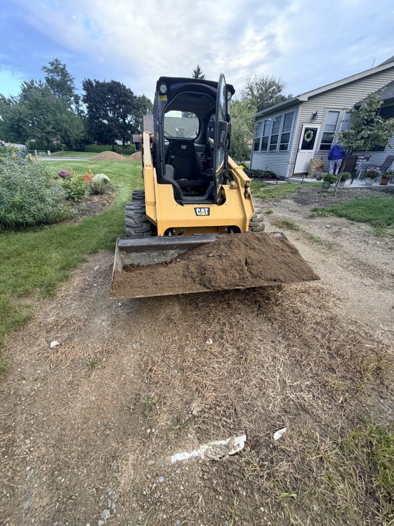 Blue Mountain LandWorks skid steer delivering a bucket of topsoil to a residential yard